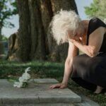 photo of an elderly woman grieving at a grave